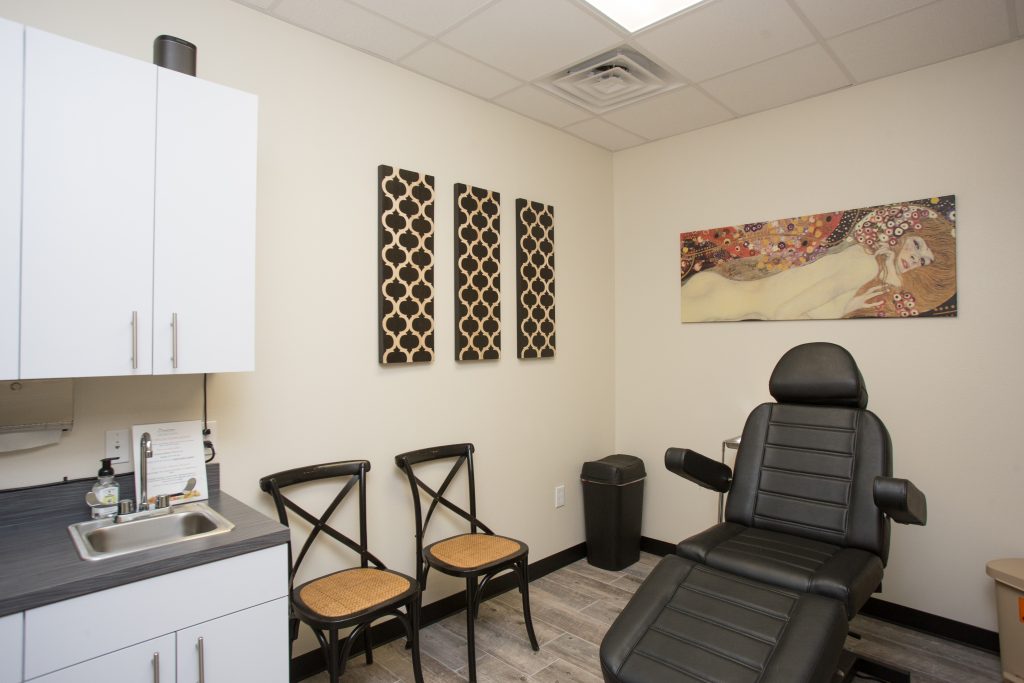 Austin med spa treatment room with black padded chair and modern artwork on the walls