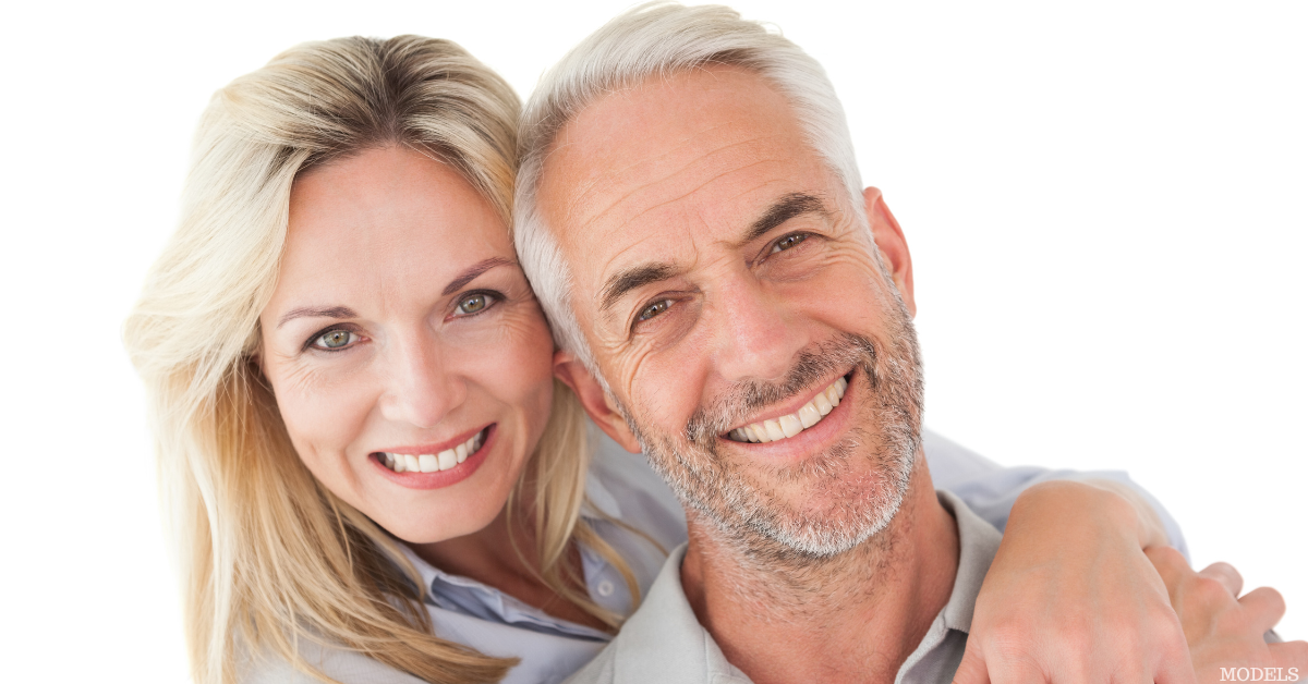 Middle aged man and woman smiling with the woman's arms wrapped around the man (models)