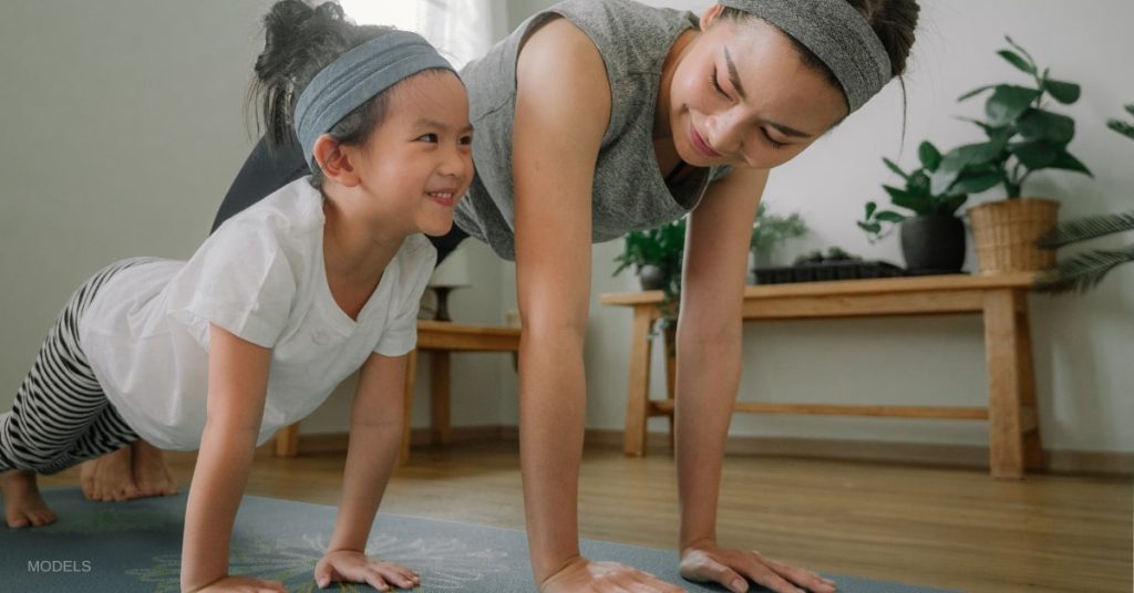 Mother and daughter (models) doing yoga together.