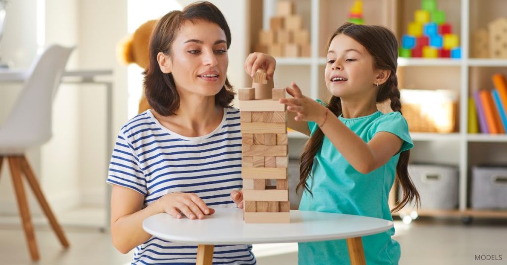 Mom and child (models) stacking blocks on the kitchen table.