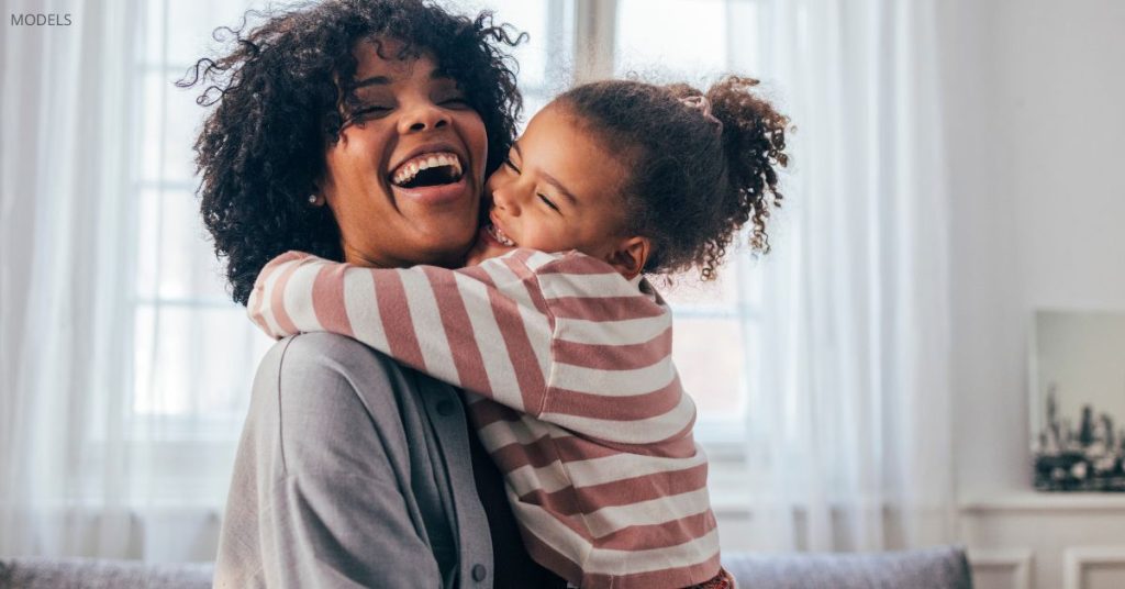 Woman and her daughter (models) sharing a warm embrace.