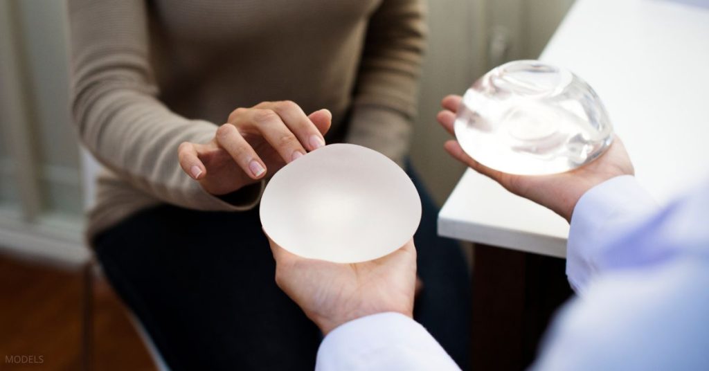 Woman consulting with a plastic surgeon (models) to select the ideal breast implant.