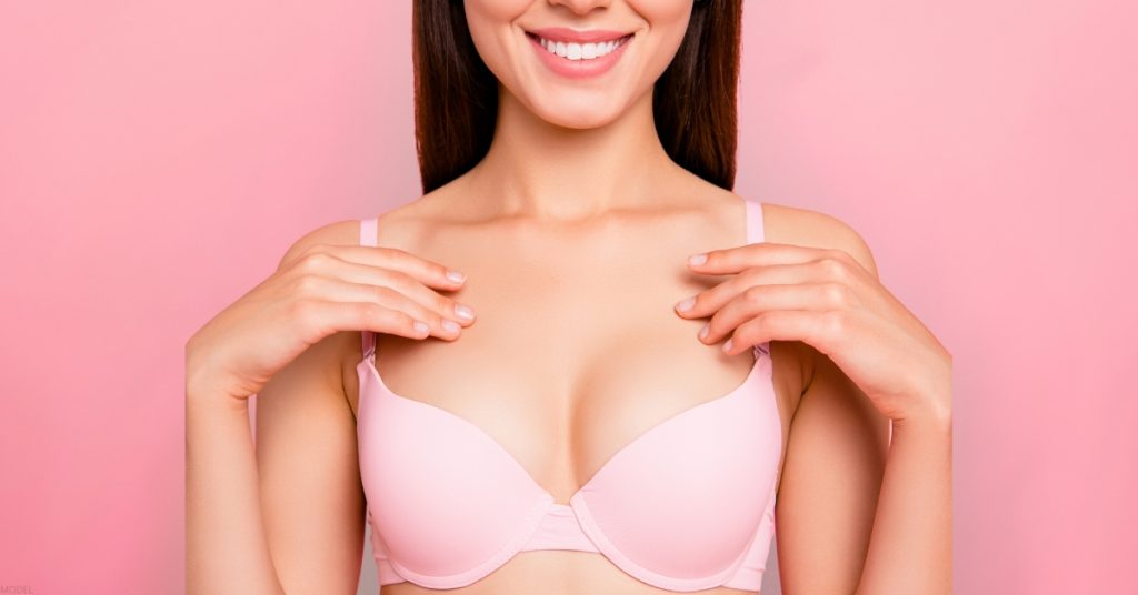 woman is wearing a pink bra on a pink background (model).