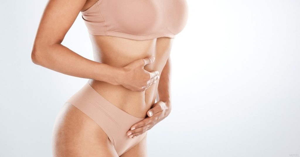 Woman with her hands on their stomach (model)